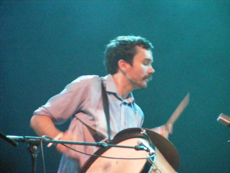man in pink shirt playing on wooden instrument