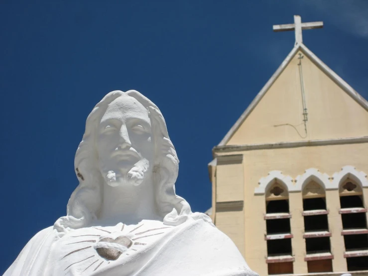 statue of jesus in front of church with cross on top