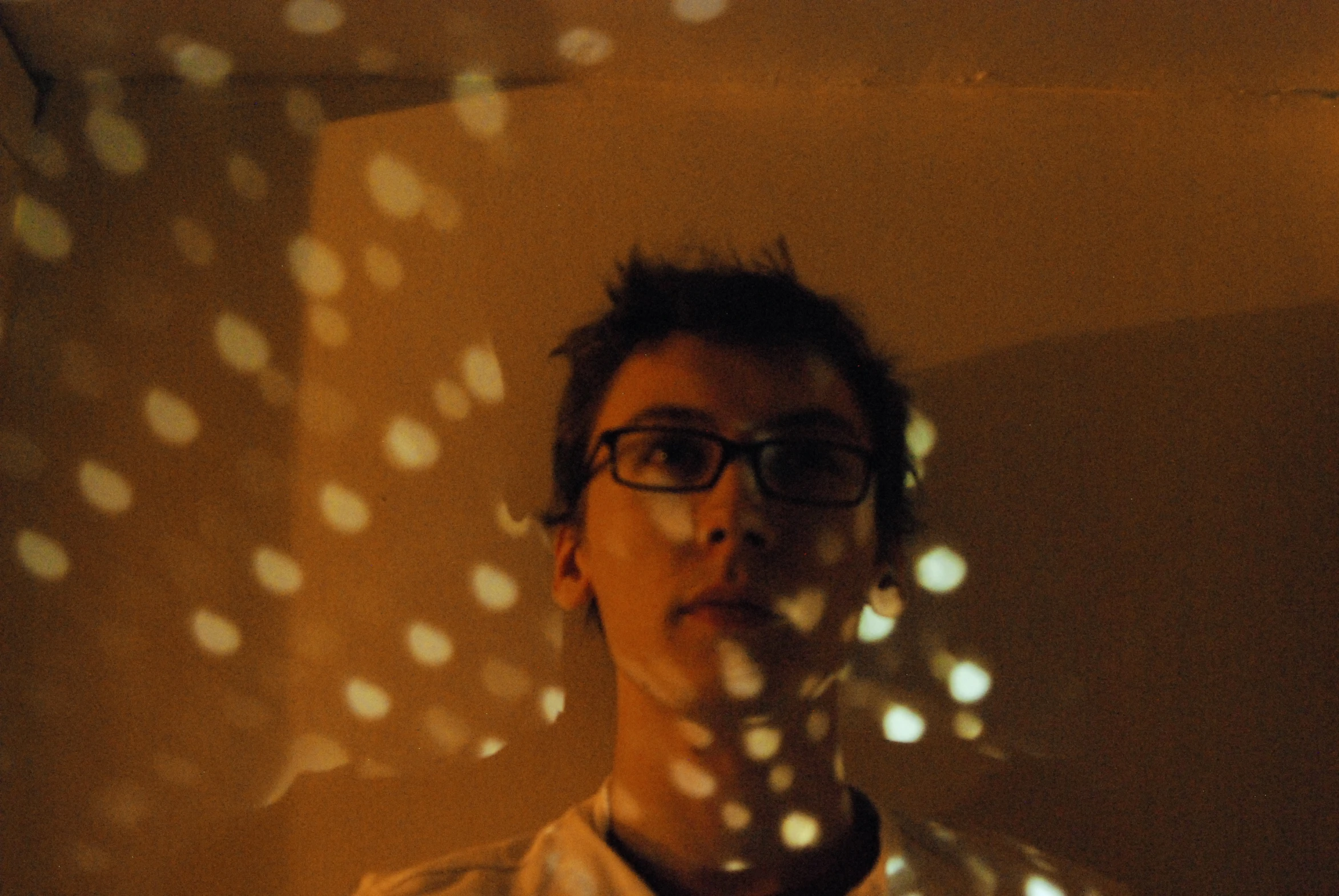 man standing under polka dot wall with camera