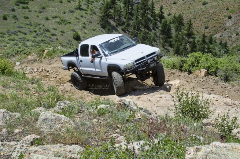 the lifted pickup is parked on the steep terrain