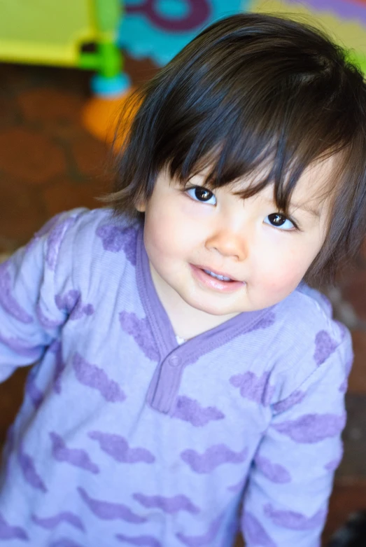 a little girl with blue eyes standing on the floor