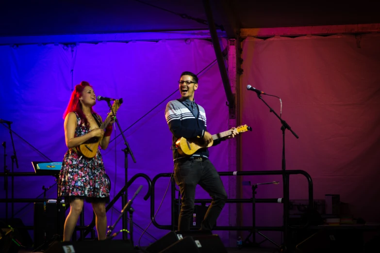 a man and woman with guitars playing a concert