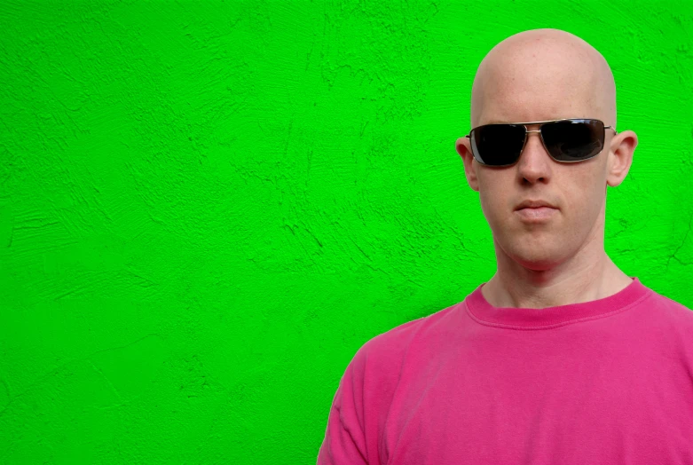 a bald man in sunglasses looks into the camera