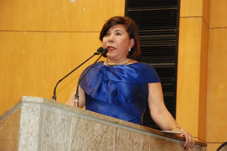 a woman in blue standing at a podium with a microphone