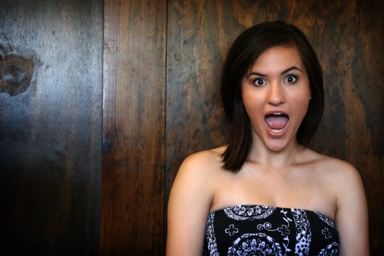 a young woman in an ornate black and blue strapless dress is sticking her tongue out