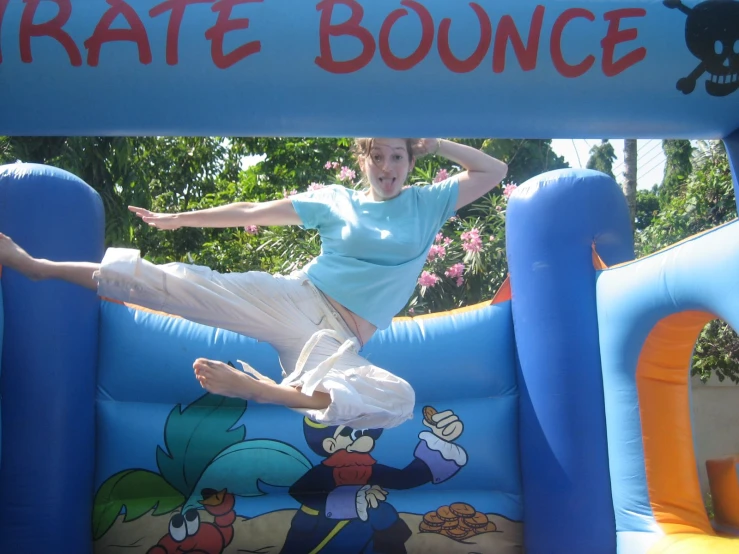 a young woman doing an acrobatic trick in an inflatable bounce