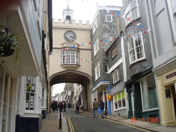 people walking down the narrow city street in front of tall buildings