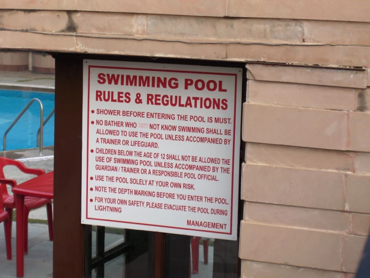 a red bench next to a swimming pool and sign