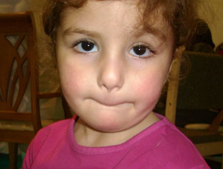 a little girl with blue eyes holding a doughnut in her hands