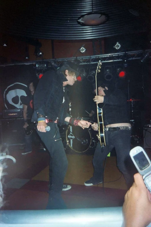 two male rock band members singing into a microphone