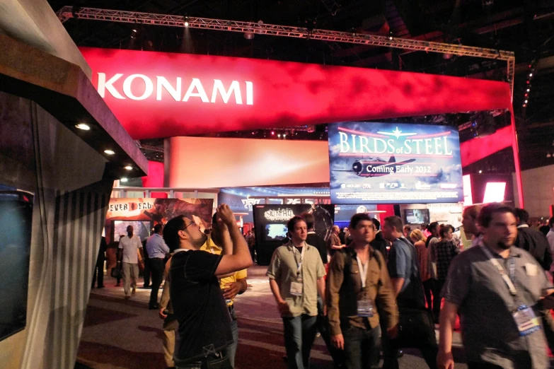 people are walking around in front of a sign at a convention