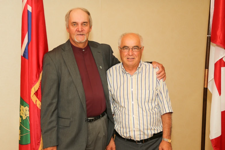 an older man with glasses next to a younger man with a suit on