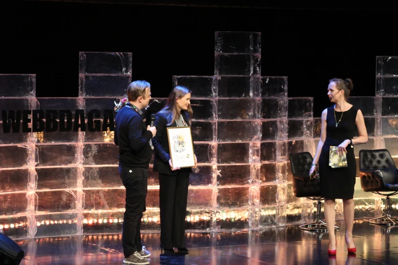 the man is holding a white plaque on stage