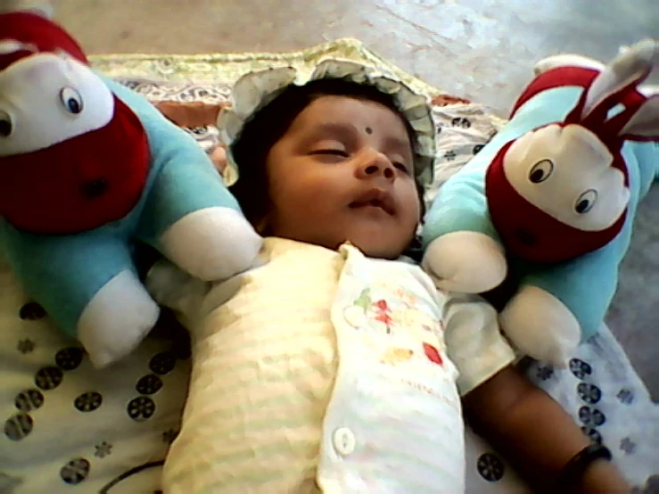 baby laying next to teddy bears in crib