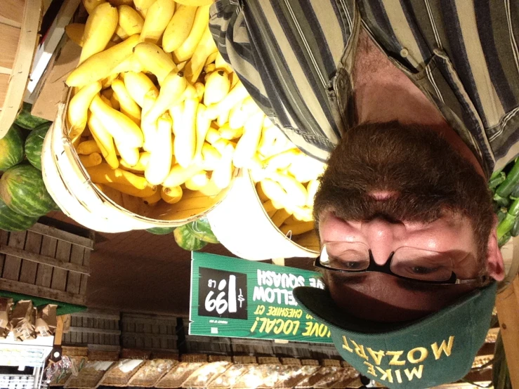 a bearded man wearing a hat next to a bunch of bananas