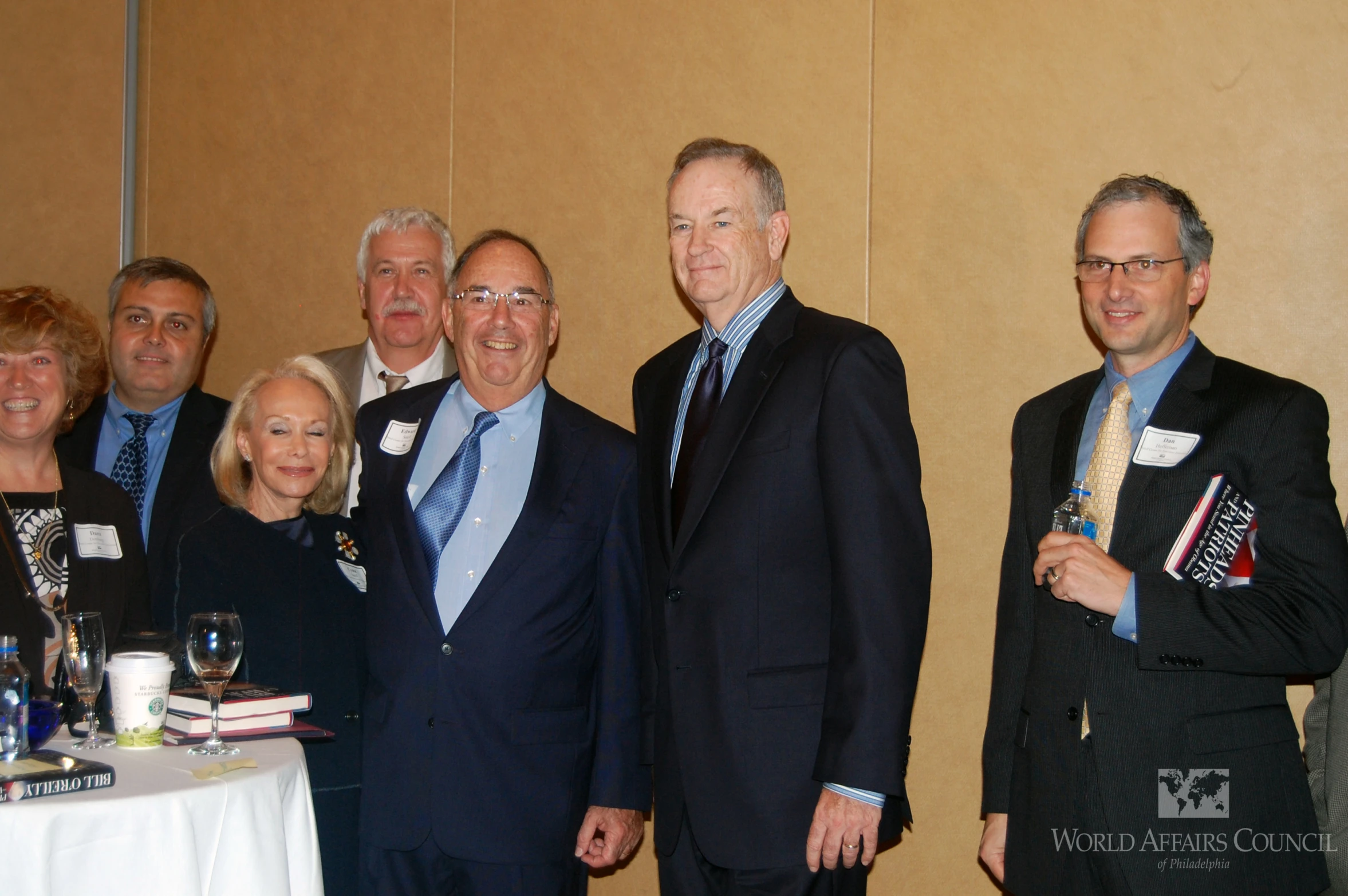 a group of business men and women stand in a room smiling