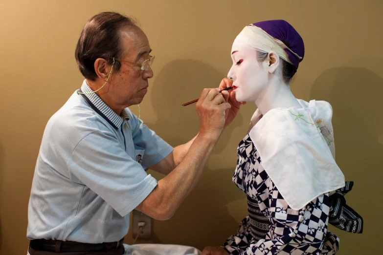 a man painting a woman's face on a model
