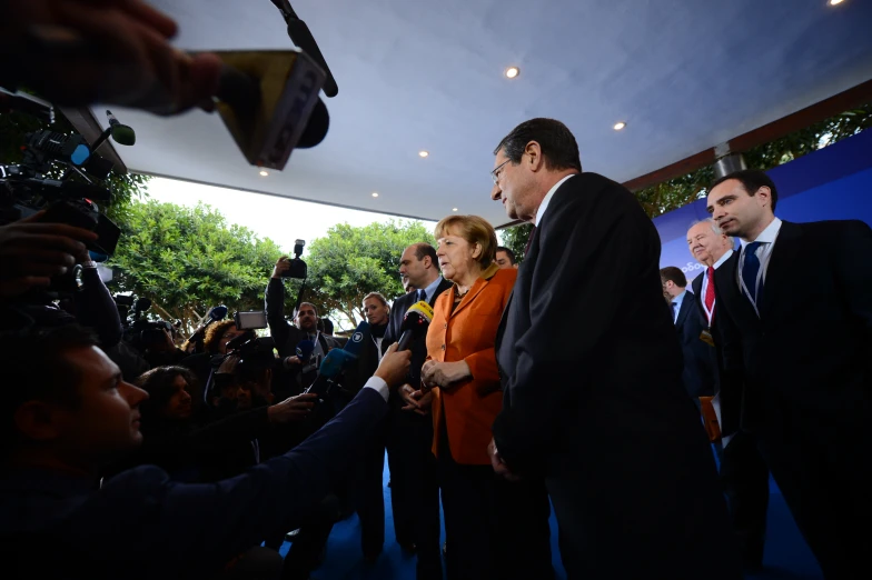 two men in suits and orange shirts shake hands with reporters