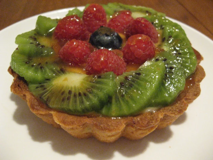 a close up of a pastry on a plate with fruit toppings