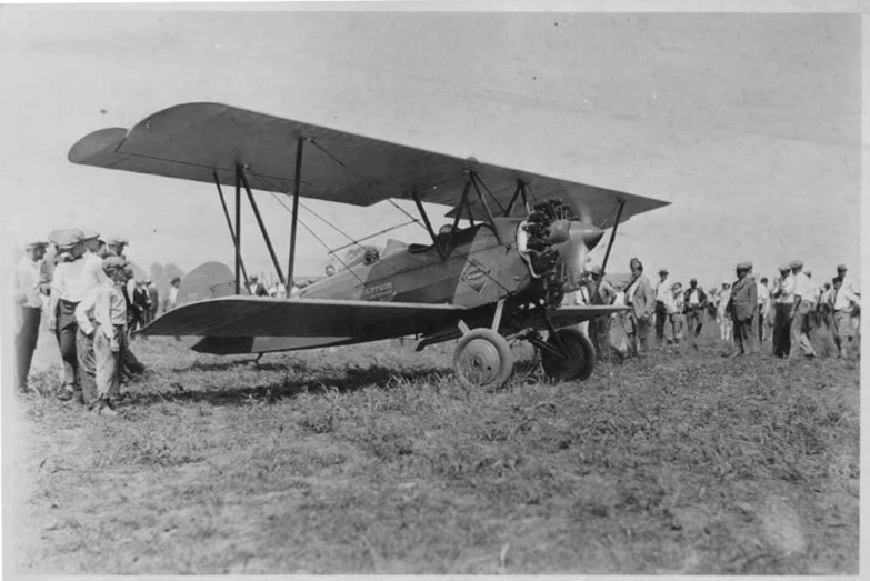 people standing by a propeller plane on top of a field