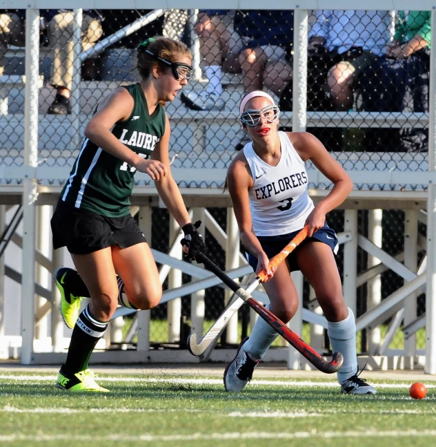 a couple of girls are playing field hockey