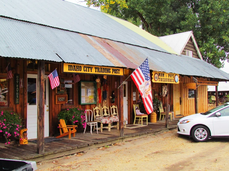 the building has several chairs outside and flowers in pots on the front of it