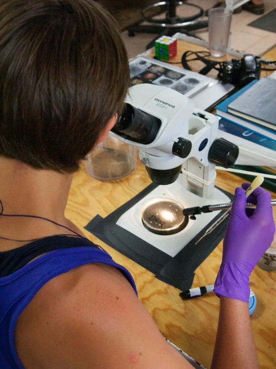 a woman looks through a magnifying glass with a pair of gloves