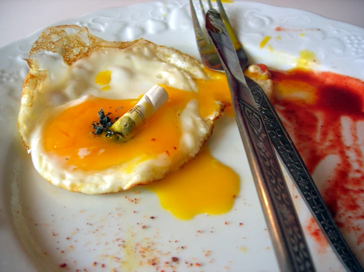 a plate with an egg on top and a knife, fork and spoon