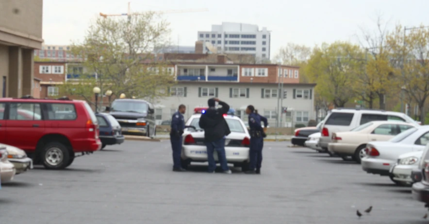 police stand outside of parked cars in a parking lot