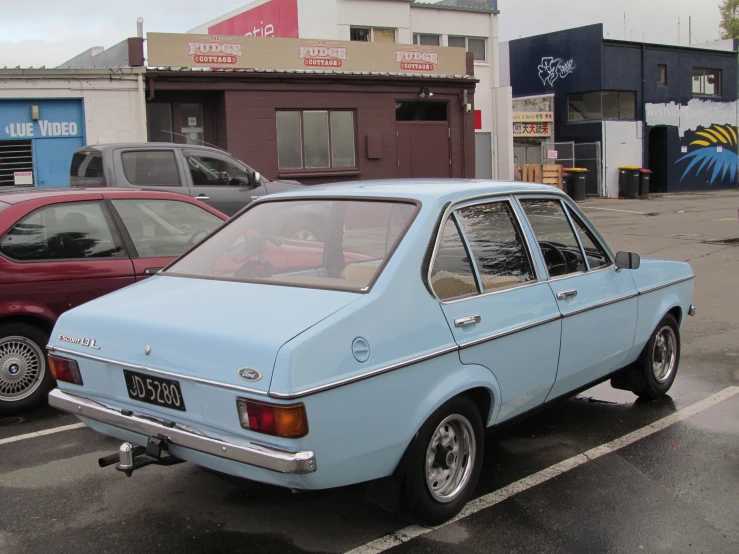 an old blue car is parked in the parking lot