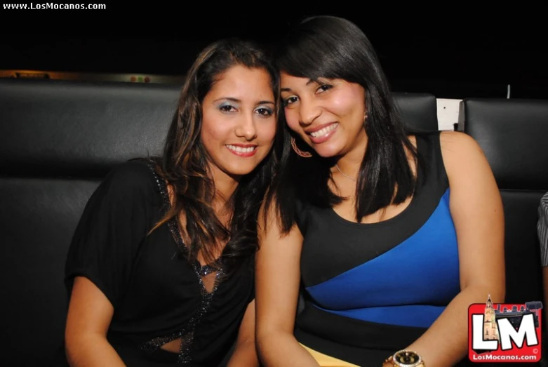 two young women pose together as they sit down at the dinner