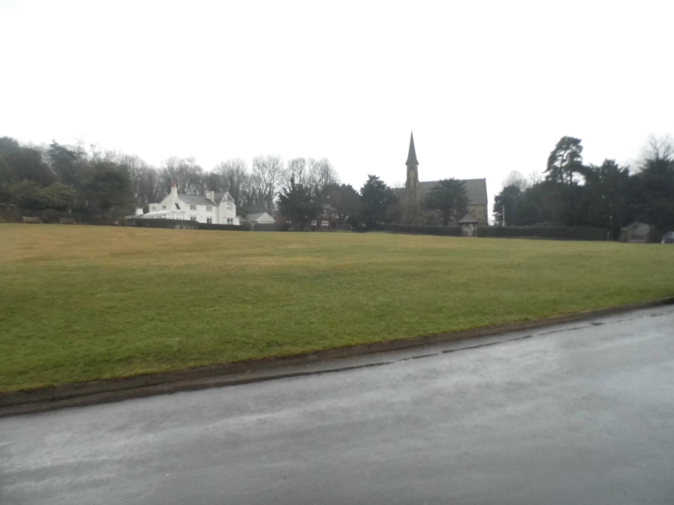 a view of a big grassy field and church