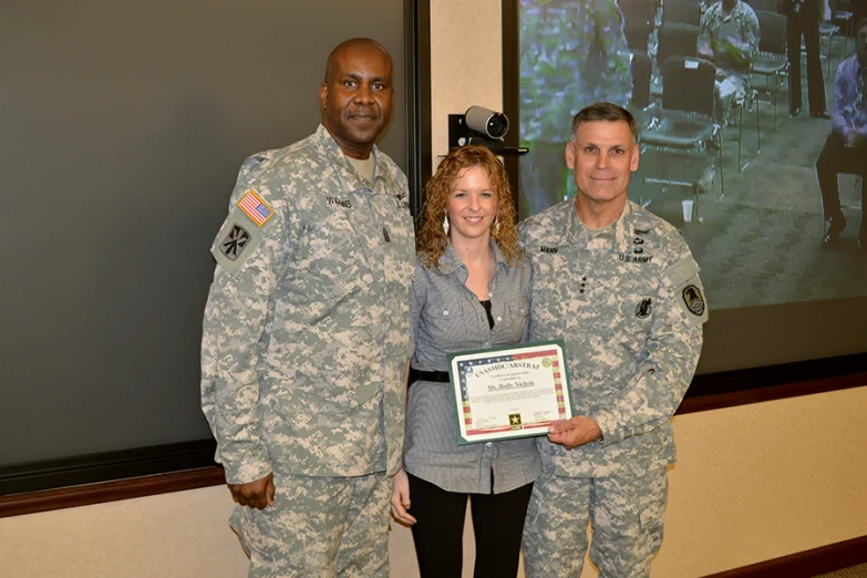 a woman in grey and military clothing holding a certificate