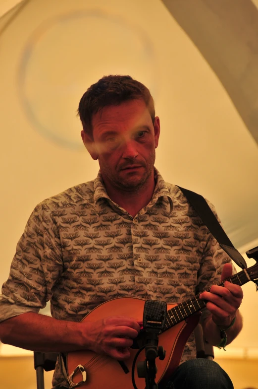 man holding an acoustic instrument and looking at the camera