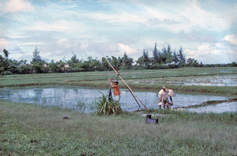 the people are on the bank of the river by their boats