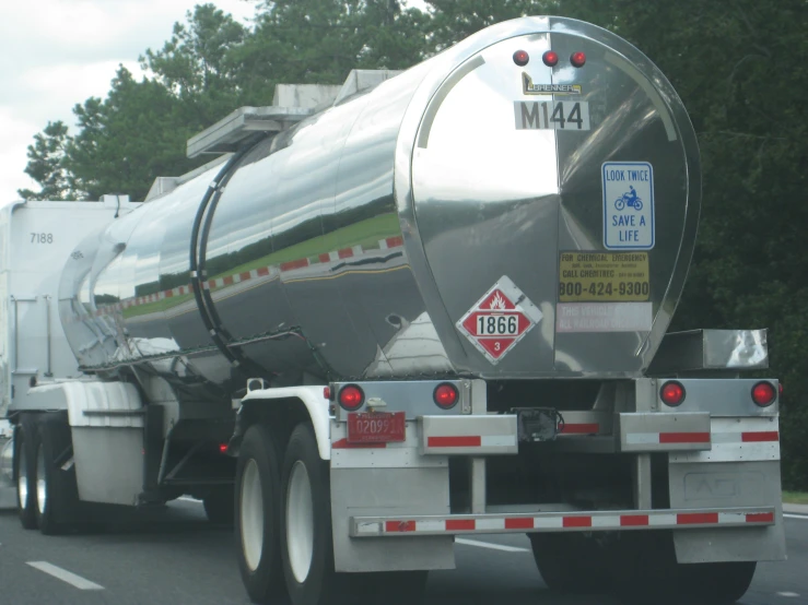 large tanker truck driving on street by trees