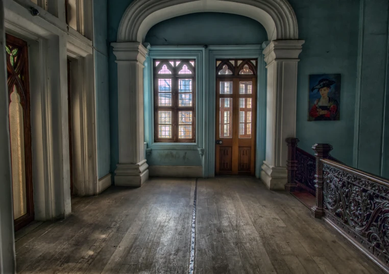 an empty room with two large windows and a wood floor