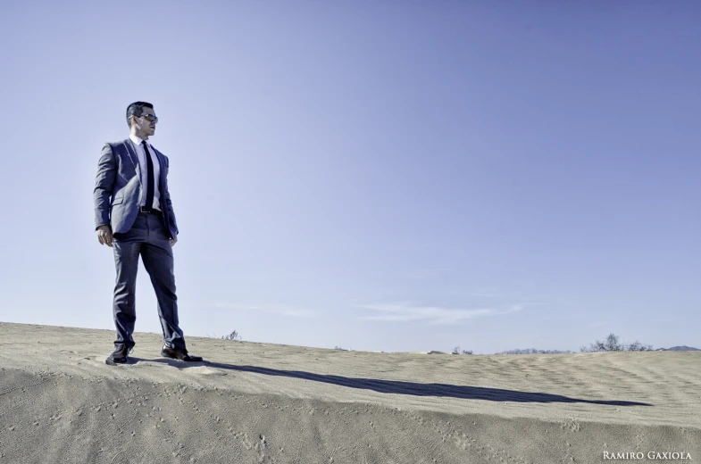 a man in a suit stands on a hill in a field