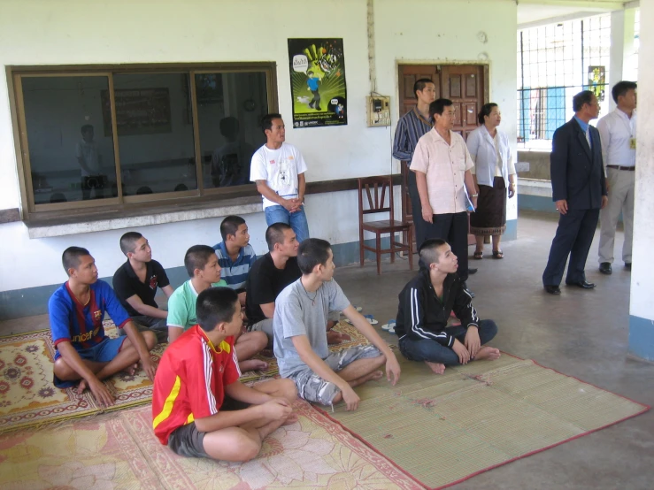 a bunch of boys sitting and standing around in a room