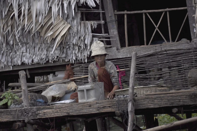 an asian woman with buckets in front of a hut