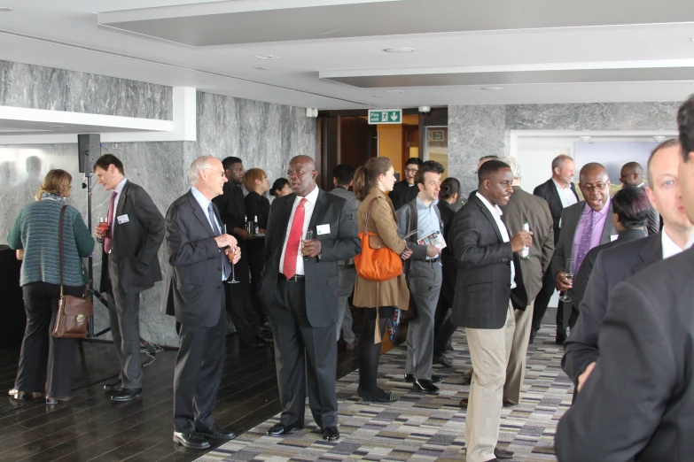 several people in suits and ties talking to each other in a lobby