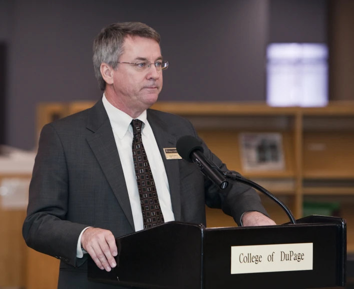 a man standing at a podium while holding a microphone