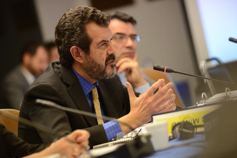 three men sitting at a table in front of microphones