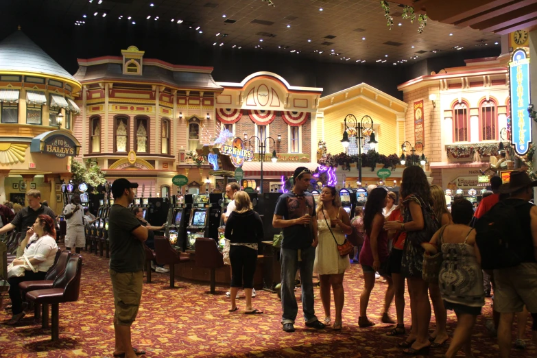 several people stand in a casino with two of them playing games