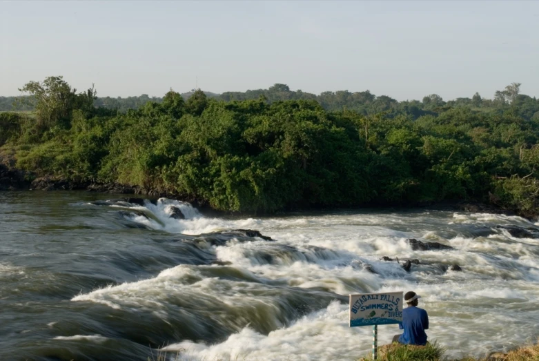 a man stands on the edge of a river with water rushing around