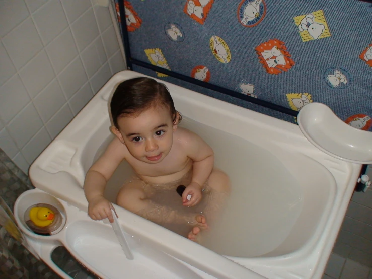 a little boy sitting in a bath tub getting his hair washed