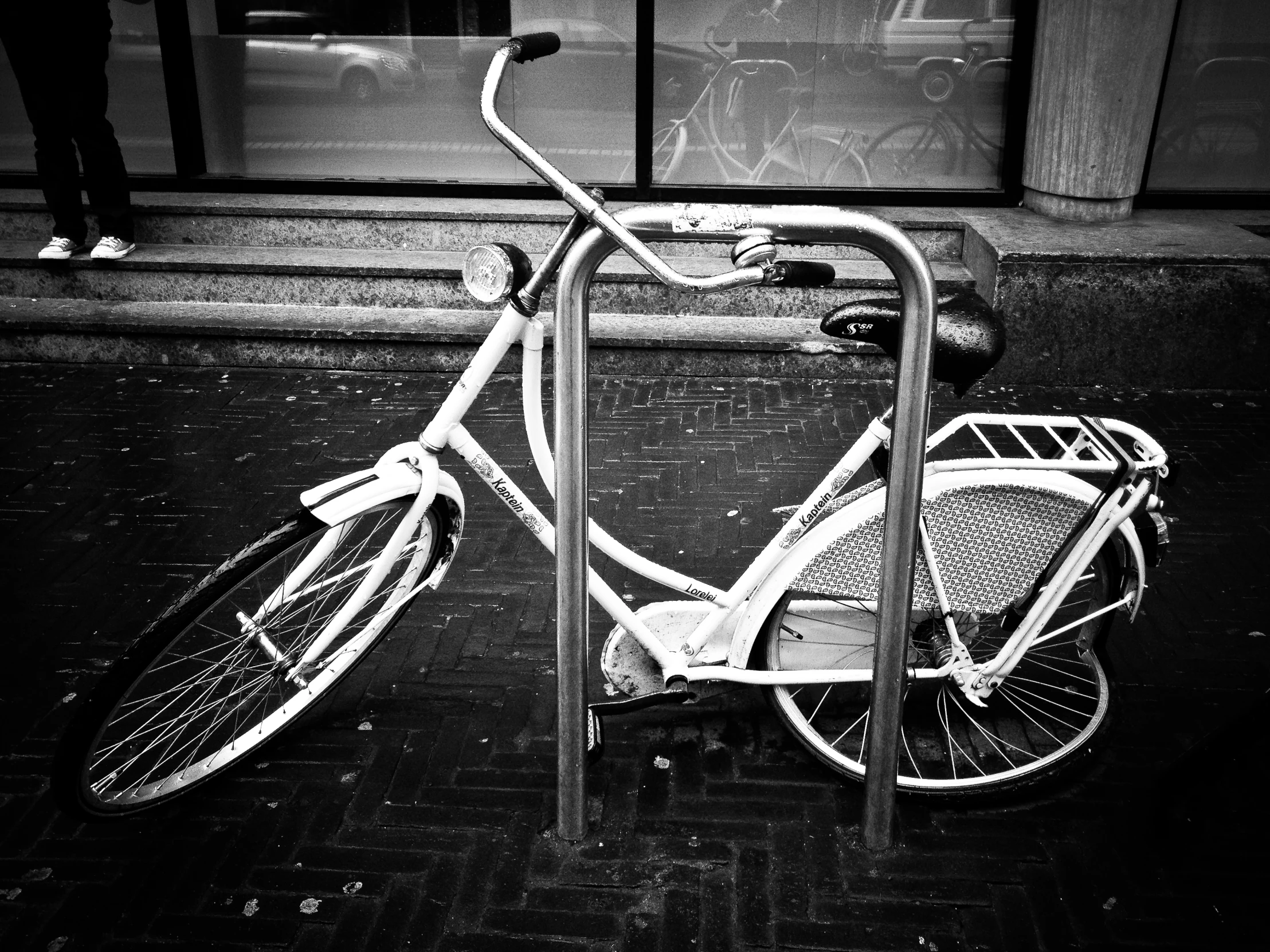 a bicycle locked to a pole on the sidewalk