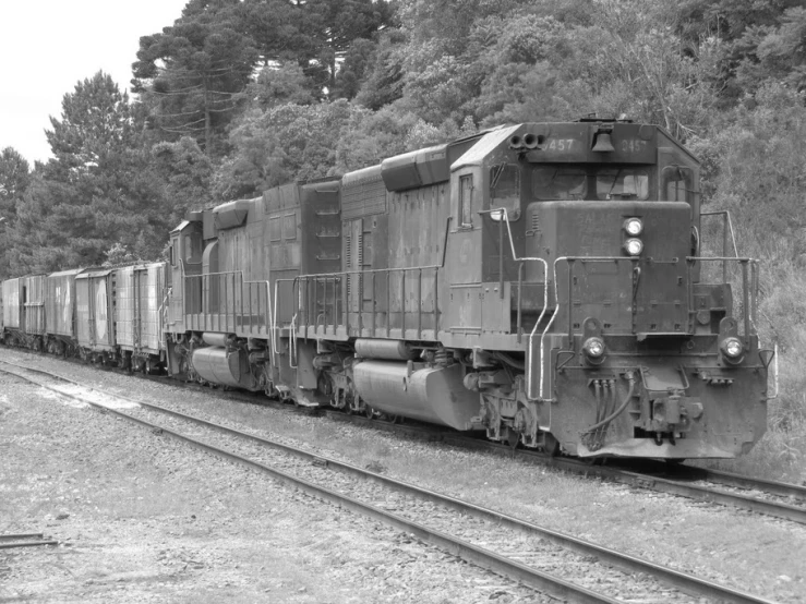 the train is traveling down the tracks by trees