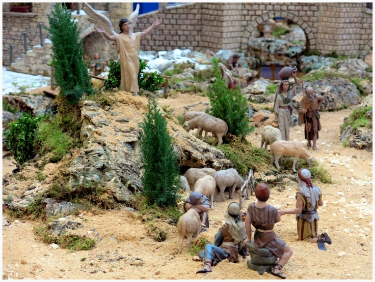 small figurines with some sheep and a man standing in the dirt