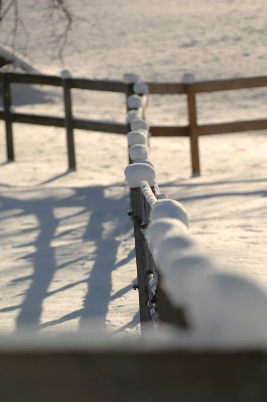 a snow covered fence next to a river and a body of water